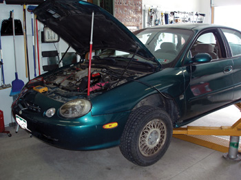 photo 1: the first diagnostic step was to lift the taurus so i could run it in gear. note the safety stands under the lift arms. 